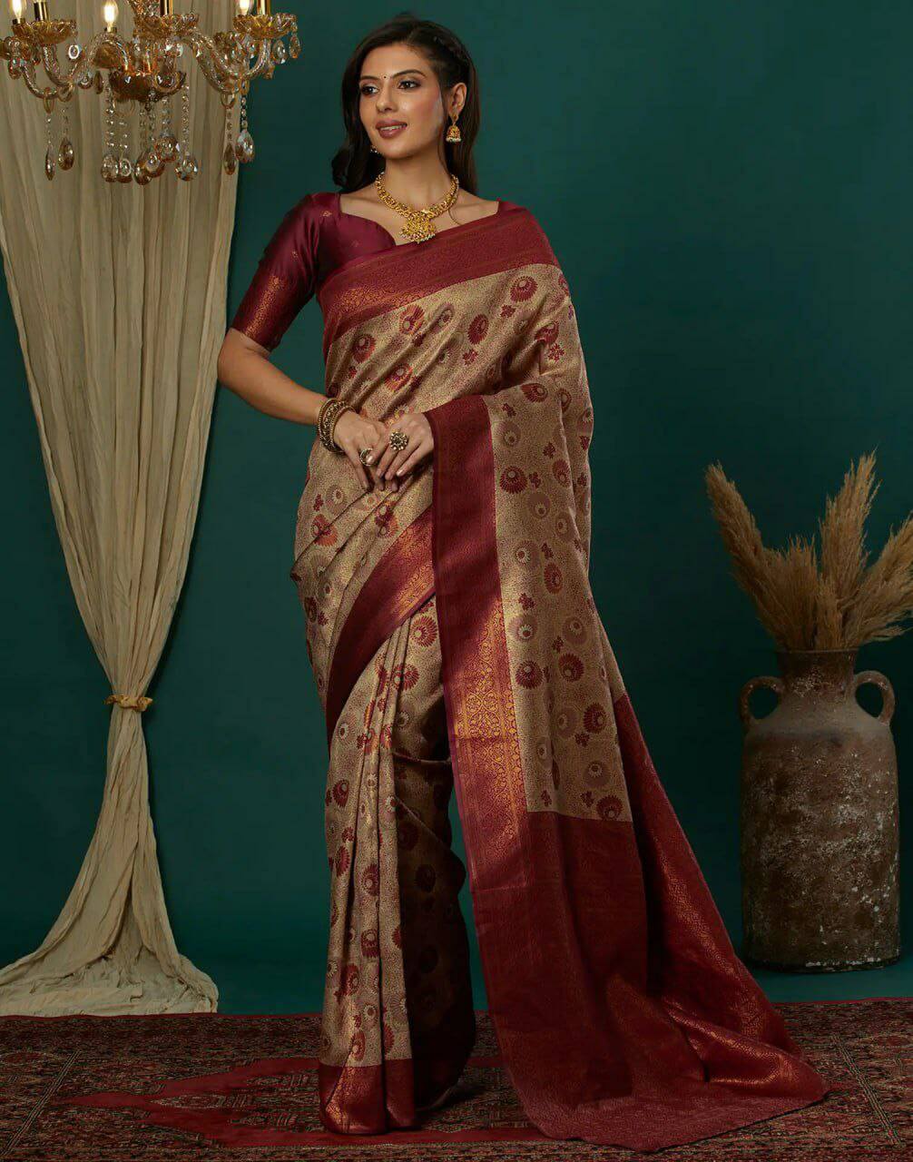 Woman in a traditional saree standing against a teal wall with decorative elements.