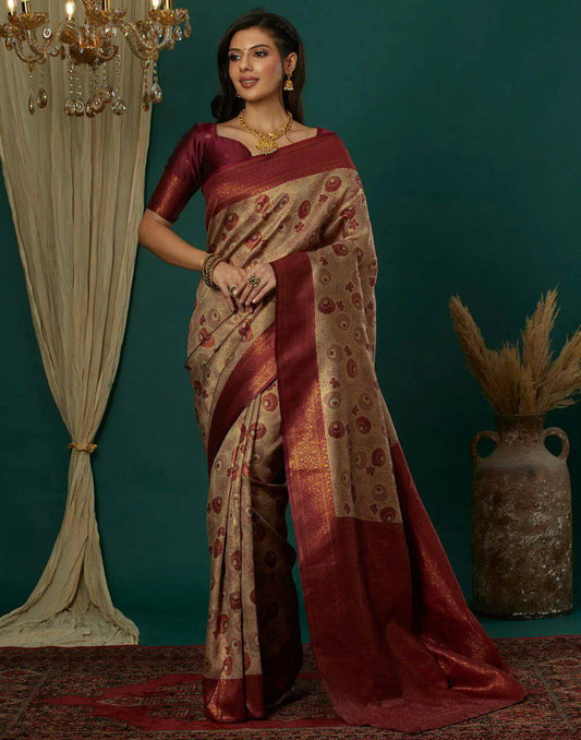 Woman in a traditional saree standing against a teal wall with decorative elements.