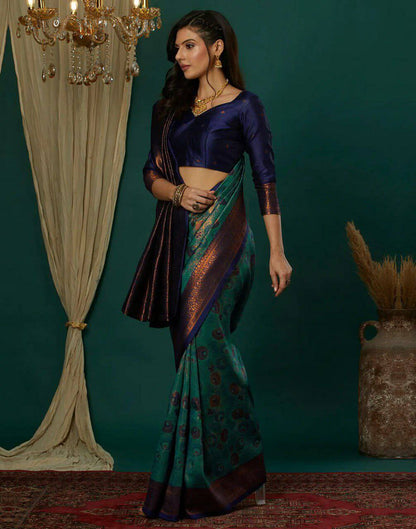 Woman in a traditional saree standing in a decorated room with a chandelier and curtains.